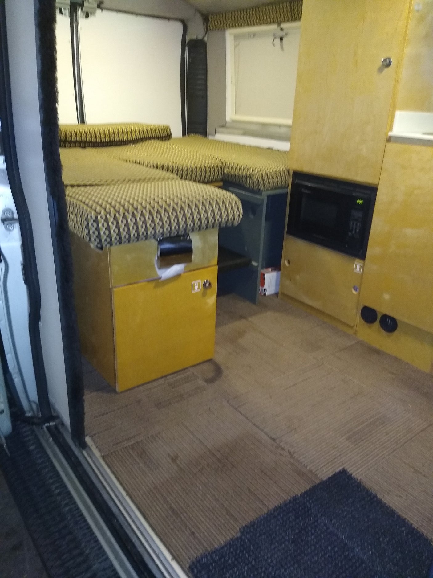 Step inside this RV rental's camper interior! Features patterned bed/seating, built-in microwave, and ample storage for your journey.
