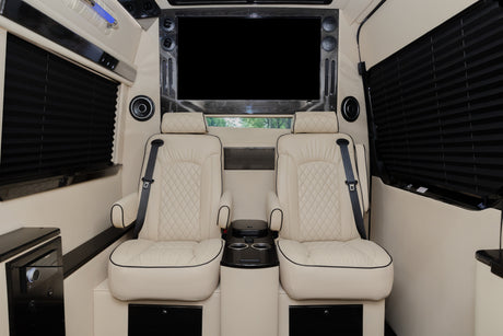Luxury rv rental: Relax in plush cream captain's chairs with seatbelts, large TV, and privacy blinds in this comfortable interior.