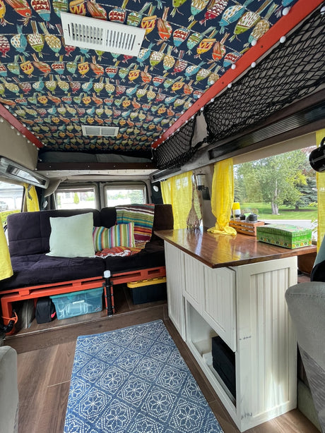 RV rental: Inside a cozy camper van featuring a vibrant bird-patterned ceiling