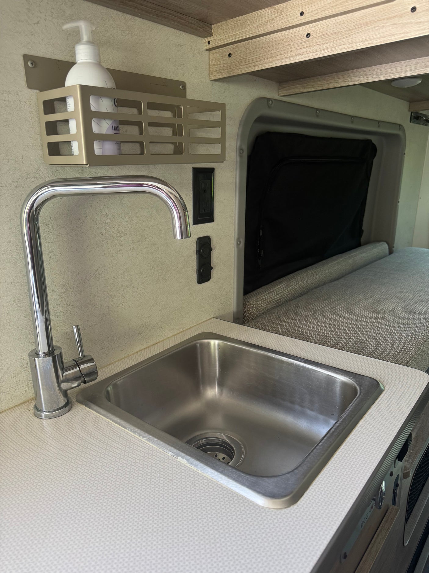 Compact RV rental kitchenette featuring a stainless steel sink, chrome faucet, and integrated storage with hand soap.