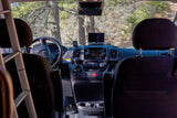 RV rental interior: driver's perspective of the dashboard, steering wheel, and a forest view through the front windshield.