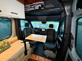 Inside this RV rental, see the campervan's compact living area with swivel front seats, a fold-out table, and cozy bench seating.