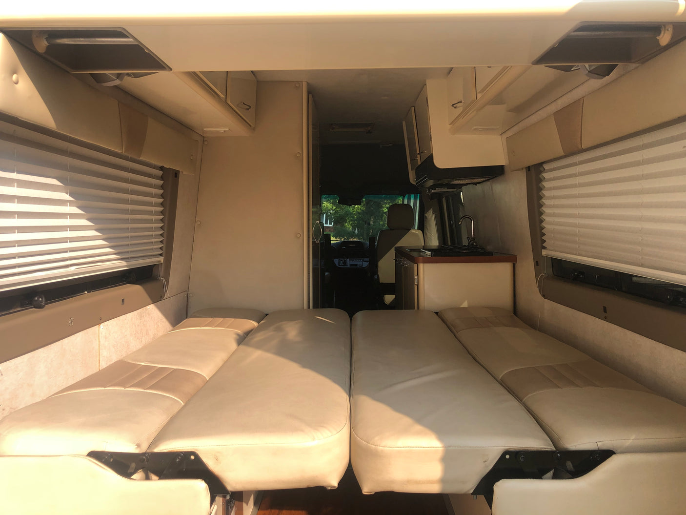 Inside this RV rental, comfortable seating converts to beds. Features include a kitchen and window blinds.