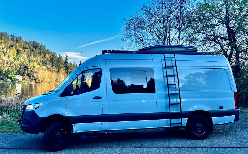White camper van parked by a scenic lake, surrounded by forested hills under a clear blue sky. Ideal RV rental for adventure. — photo 7