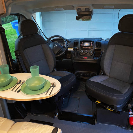 Compact rv rental interior: swivel front seats converted to a dining area with a set table, ready for travel meals.