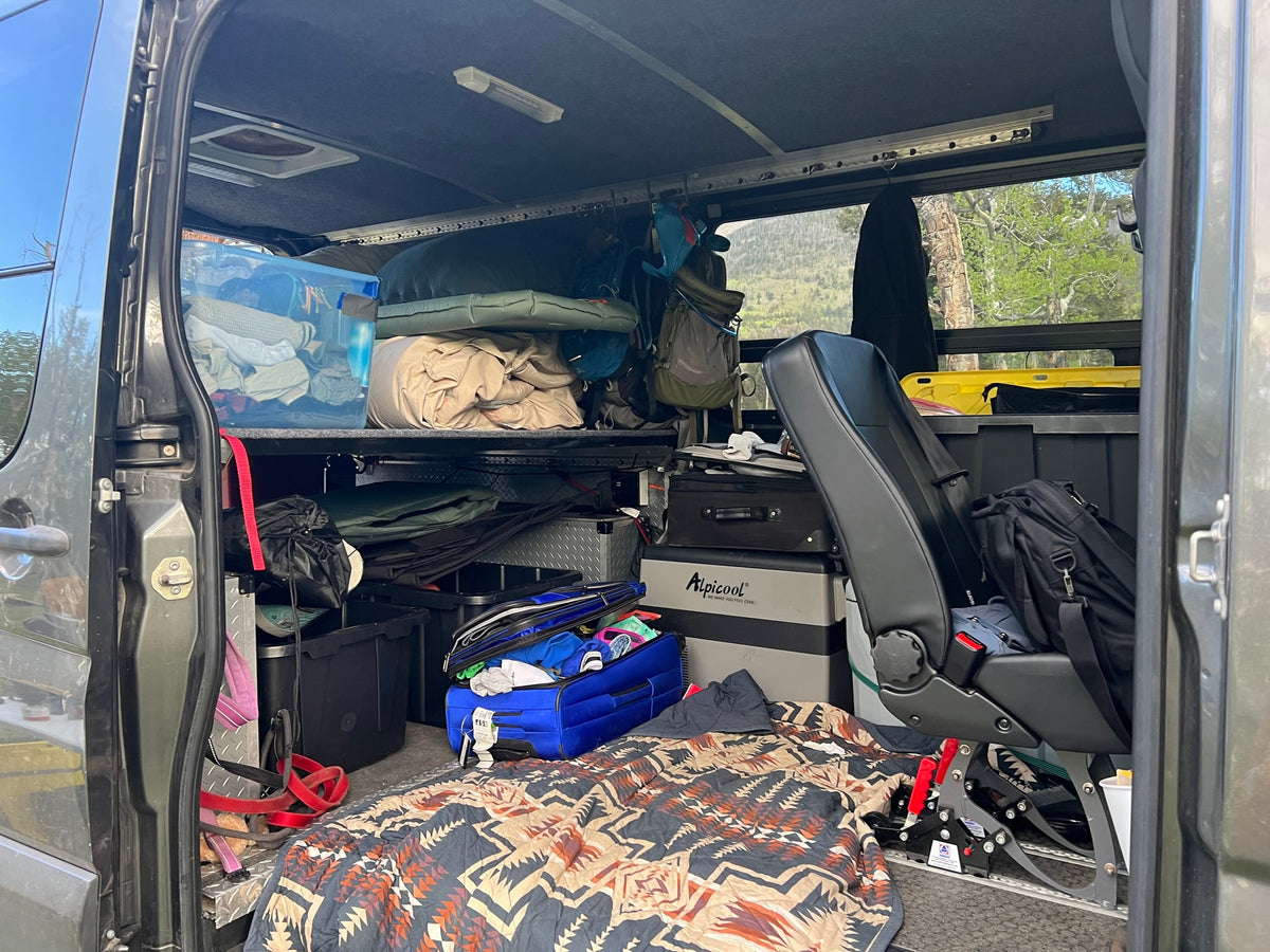RV rental interior packed with camping gear, a fridge, and blankets, ready for a rugged outdoor adventure. — photo 13