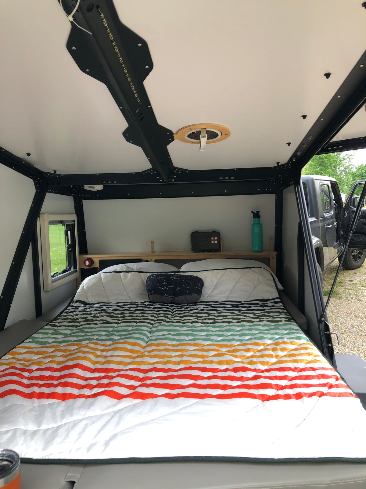 Cozy RV rental camper interior with a colorful striped bed, overhead fan, and integrated lighting for comfortable travels. — photo 4
