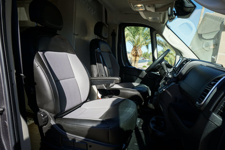 Spacious RV rental interior with driver & passenger seats, dashboard, and a sunny palm tree view.