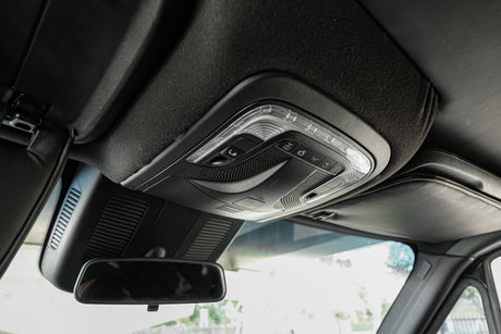 Detailed view of an RV rental's overhead console, featuring interior lights, a control panel, and a rearview mirror.