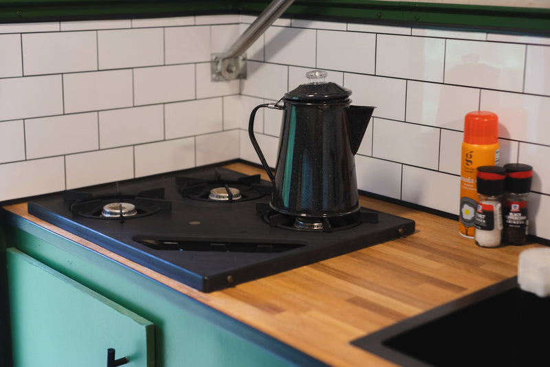 RV rental kitchen featuring a two-burner stove, classic coffee pot, wood counters, and white tiled backsplash. Great for road trips. — photo 7