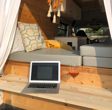 Cozy RV rental interior with laptop & wine for remote work and relaxation. Perfect for mobile living!