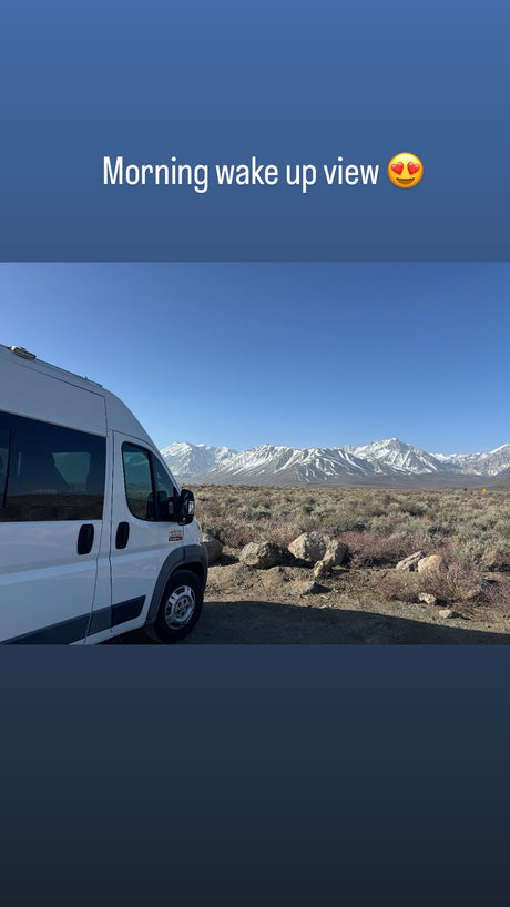 Scenic morning wake-up from an RV rental! White camper van faces majestic snow-capped mountains in desert.