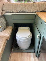 Compact RV rental features a hidden composting toilet on a pull-out base, maximizing space under the bed.