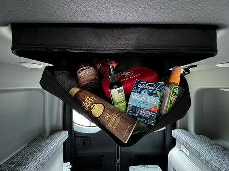 RV rental overhead storage holds travel essentials: sunscreen, bug repellents, a first aid kit, and Yahtzee.