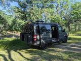 Explore the outdoors with this gray camper van RV rental, equipped with a mountain bike, parked under trees.