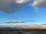 Expansive desert with rugged mountains under a dramatic sky. A white **rv rental** is parked, ready for wilderness adventure.