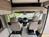 Spacious RV rental interior looking forward into the cockpit with swiveling front seats, perfect for comfortable travel.