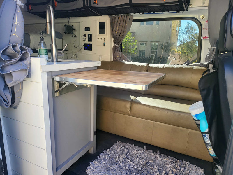 RV rental interior showcasing a compact camper van's functional design: kitchen sink, fold-out table, and cozy sofa. — photo 10