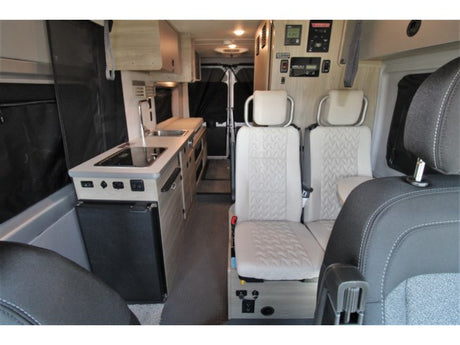 Interior of a modern rv rental, featuring a compact kitchen with sink/stove, and a comfortable living area with seating.