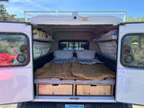 Cozy rv rental truck camper setup with sleeping bags, pillows, and storage drawers. Perfect for outdoor adventure camping.