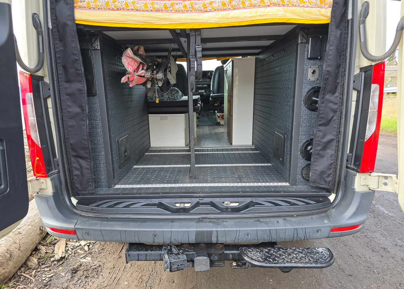 RV rental's rear interior with open doors, showing textured walls, floor lighting, gear storage, and electrical panel. — photo 8