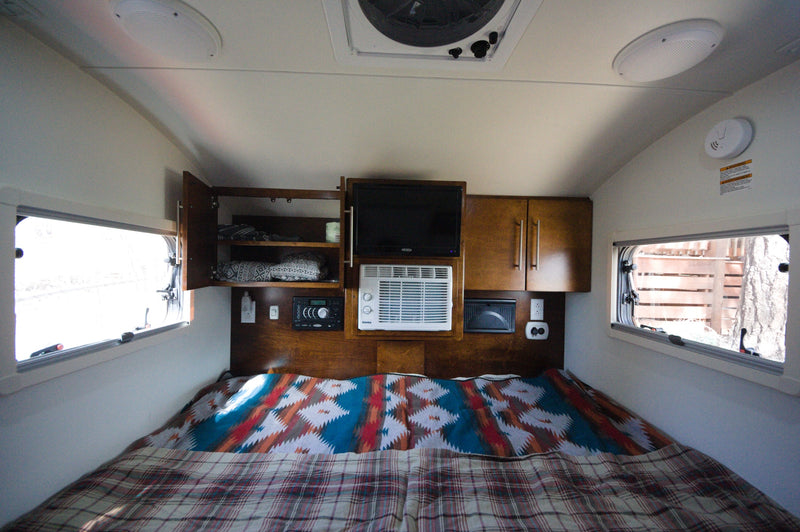 Cozy rv rental interior: a comfortable bed, TV, AC, and ample storage cabinets make for ideal travel accommodations. — photo 10
