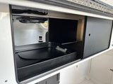 RV rental: Well-organized interior storage compartment with a large black utility tray and sliding access panel.