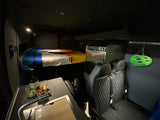 Cozy RV rental interior showing a raised bed, kitchen, passenger seats, and bike storage, perfect for adventure.