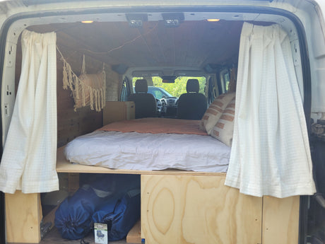 Cozy RV rental interior featuring a comfortable bed, wood paneling, and ample storage for your next adventure.