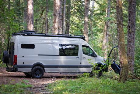 RV rental camper van parked in a lush forest with an open side door revealing a hanging chair. Ready for adventure.