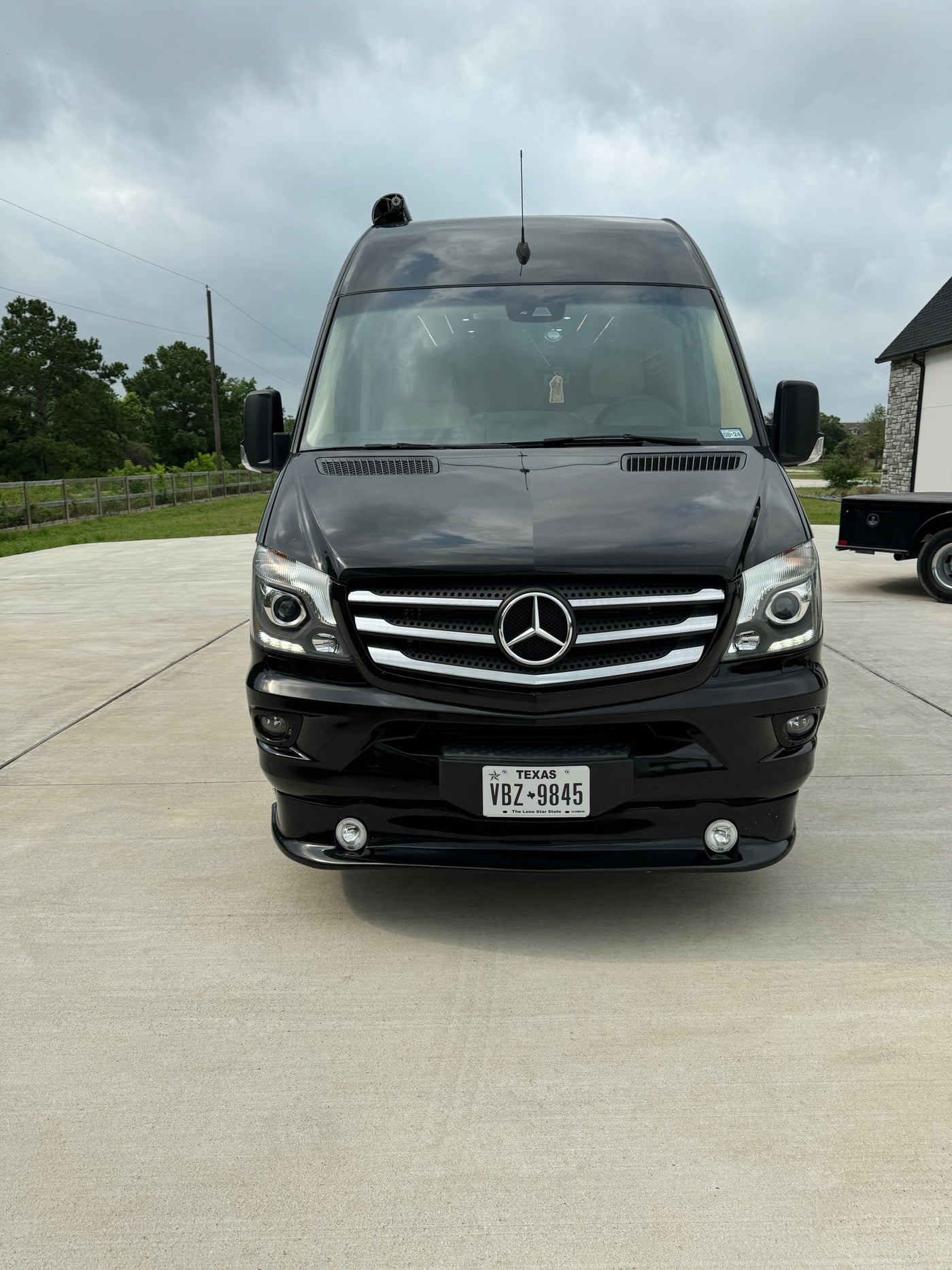 Front view of a black Mercedes Sprinter van, a sleek RV rental. Parked on concrete, it features a Texas license plate VBZ 9845. — photo 2