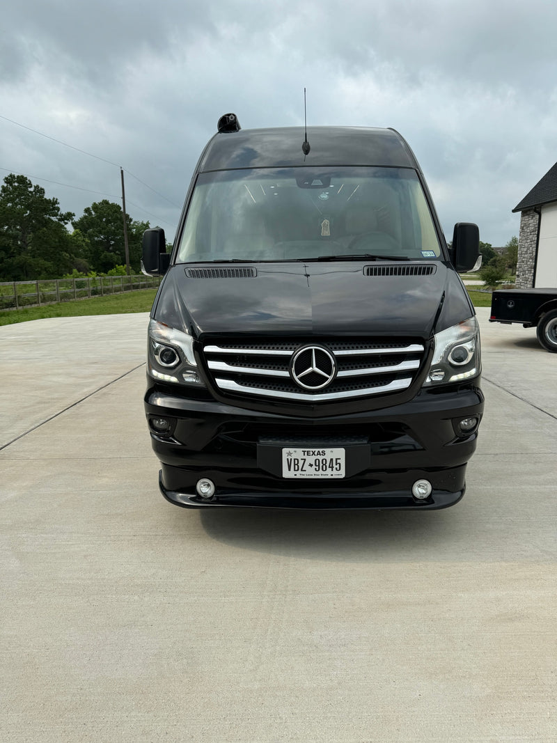 Front view of a black Mercedes Sprinter van, a sleek RV rental. Parked on concrete, it features a Texas license plate VBZ 9845. — photo 2