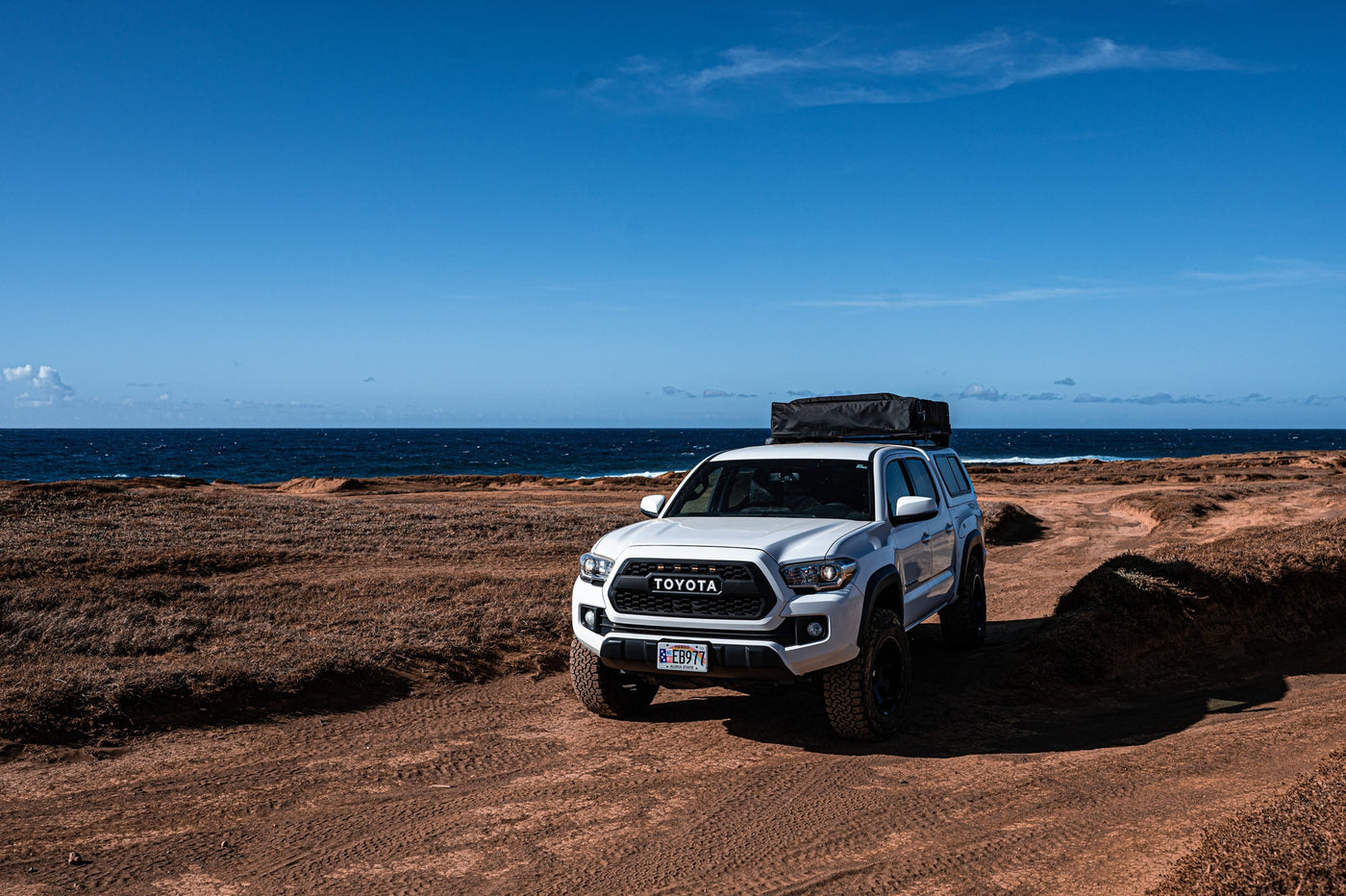 White Toyota Tacoma truck with rooftop tent on an arid coastal dirt track, ideal for your next RV rental adventure. — photo 11