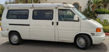 Experience adventure in this white VW T4 camper van, featuring a pop-top roof and awning, ideal for your next RV rental.