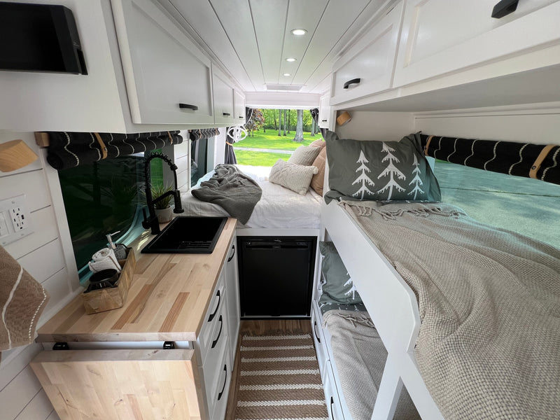 Bright rv rental interior with a modern kitchen, bunk beds, and overhead storage. Ideal for adventurers. — photo 18