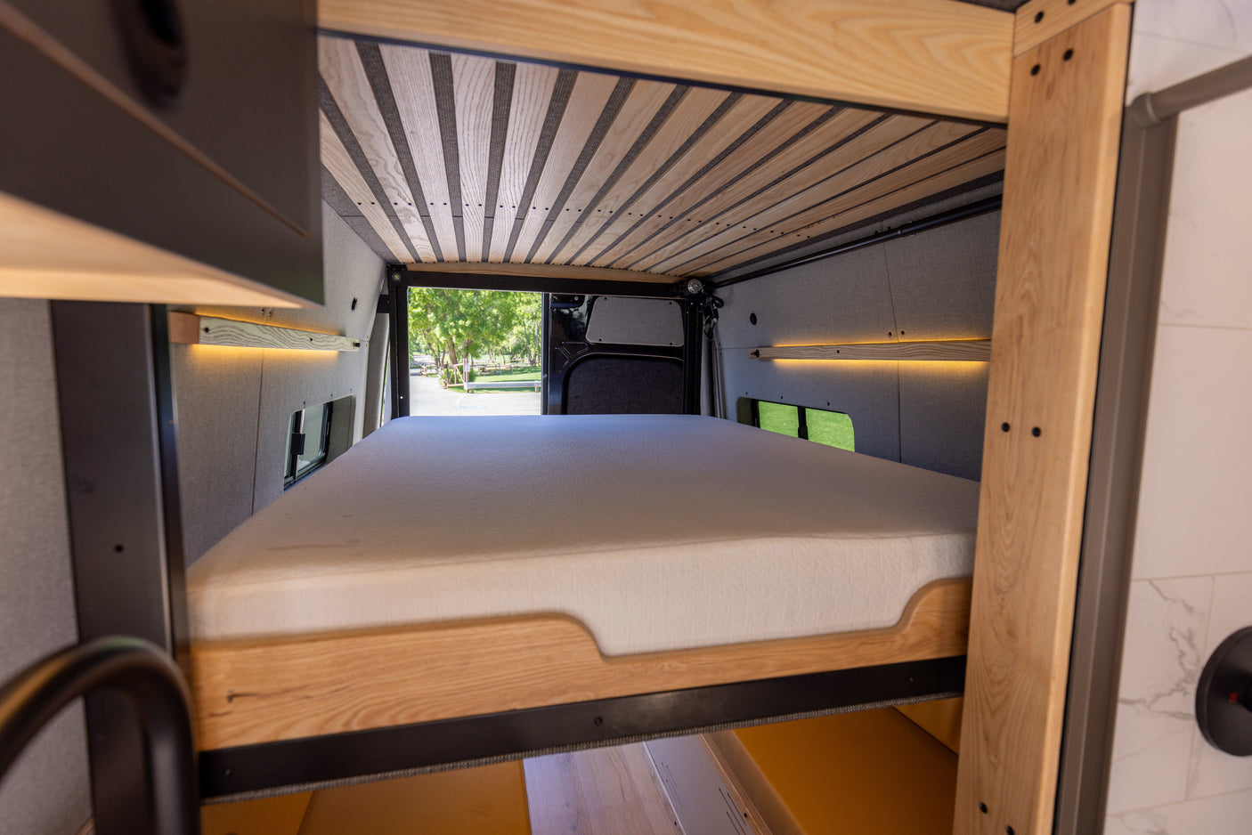 Cozy RV rental interior with a comfy bed, wood accents, and a view of the outdoors.