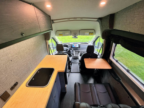 Spacious RV rental interior with kitchen, table, and driver's cabin, ideal for mobile living and travel.