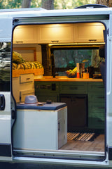 Cozy RV rental interior with a bed, kitchen, built-in fridge, and seating area, designed for comfortable adventures.