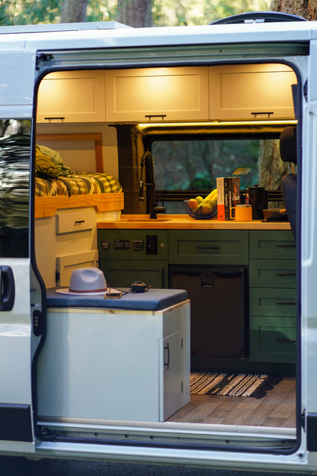 Cozy RV rental interior with a bed, kitchen, built-in fridge, and seating area, designed for comfortable adventures.