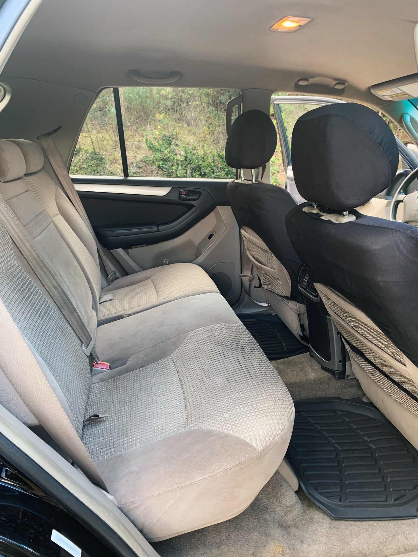 Rear passenger interior of a spacious SUV, ideal for an rv rental, with tan seats, black headrest covers, and rubber floor mats.