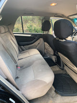 Rear passenger interior of a spacious SUV, ideal for an rv rental, with tan seats, black headrest covers, and rubber floor mats.
