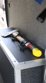 Tool storage in an RV rental: An axe with a multi-colored handle (blue, white, red, green, yellow) is securely mounted.