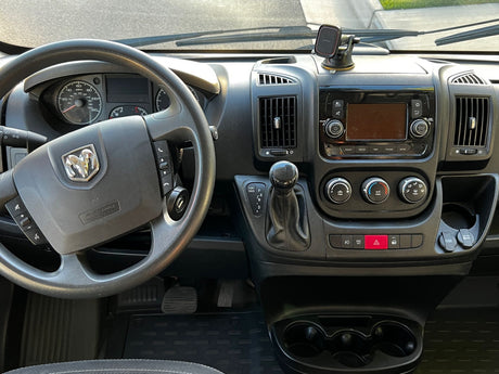 Detailed view inside an RV rental van: driver's dashboard, steering wheel, media console, climate controls, and gear shifter.