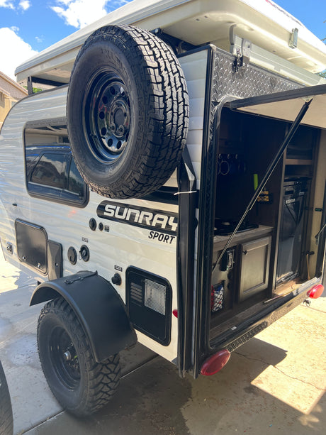 White Sunray Sport teardrop camper RV rental with an open outdoor kitchen at the rear and a rooftop tent.