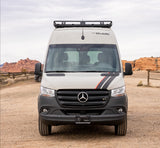 Front view of a Mercedes-Benz Sprinter RV rental van, "The Guide", with a roof rack, in a desert landscape.