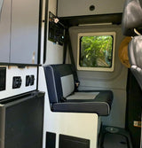 RV rental: Modern camper van interior with comfy bench seating, control panels, power outlets, and a window view of nature.