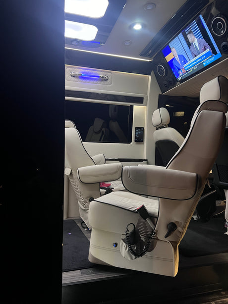 Luxury RV rental interior with comfy captain's chairs, TV, and ambient lighting, perfect for travel.