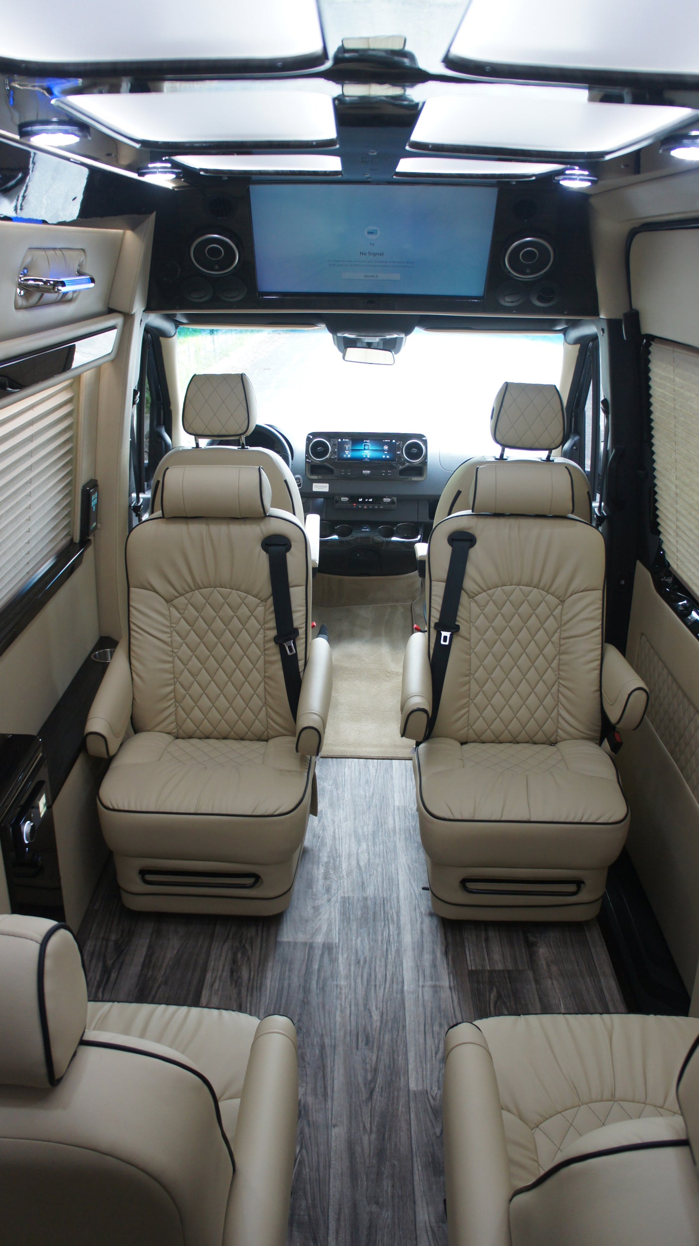 Step inside this RV rental: luxurious interior with quilted leather captain chairs, wood-style floor, and front entertainment.