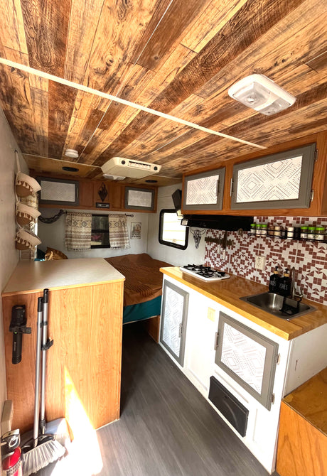 RV rental: Bright, renovated interior with wood plank ceiling, kitchen, and bed, offering a cozy travel experience.