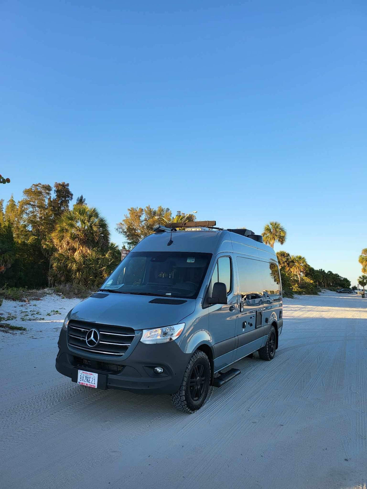 Gray Mercedes Sprinter RV rental on a sandy beach road among palm trees under a clear blue sky. — photo 4